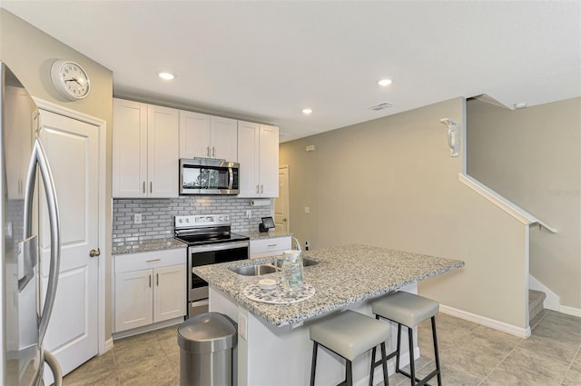 kitchen featuring sink, an island with sink, light stone counters, white cabinetry, and stainless steel appliances