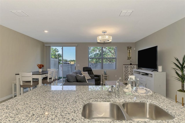 kitchen featuring plenty of natural light, light stone counters, and sink