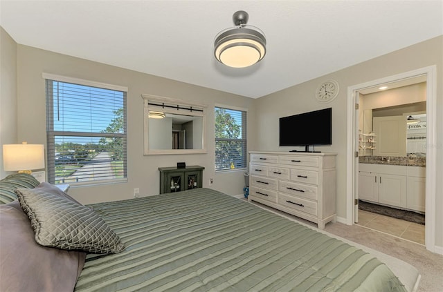 bedroom with connected bathroom and light carpet