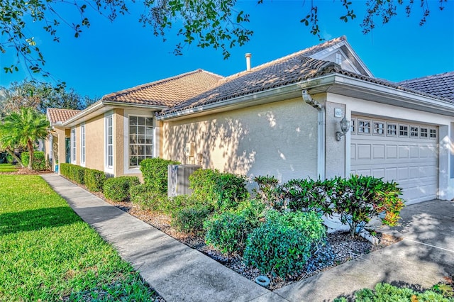 view of home's exterior featuring a lawn, central AC unit, and a garage