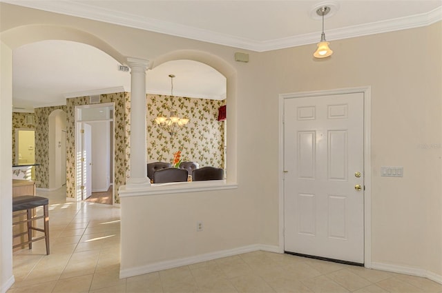 tiled foyer entrance with a chandelier, decorative columns, and ornamental molding