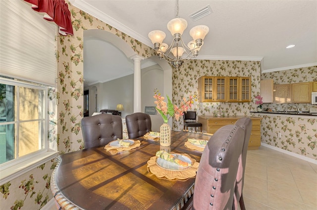 dining space with decorative columns, an inviting chandelier, and crown molding