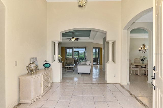 entrance foyer featuring ceiling fan with notable chandelier, light tile patterned floors, and ornate columns