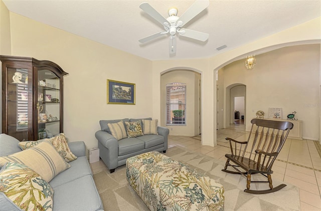 tiled living room with plenty of natural light and ceiling fan with notable chandelier