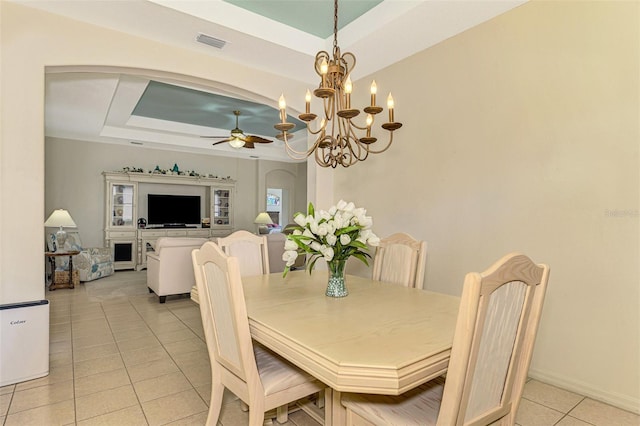 dining area with a tray ceiling, light tile patterned floors, and ceiling fan with notable chandelier