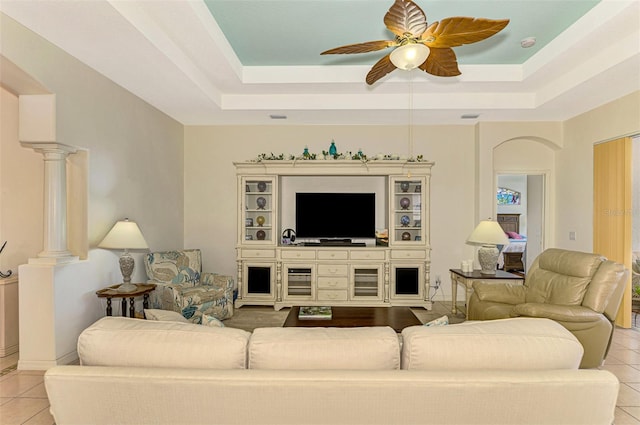 living room featuring light tile patterned floors, decorative columns, and a raised ceiling