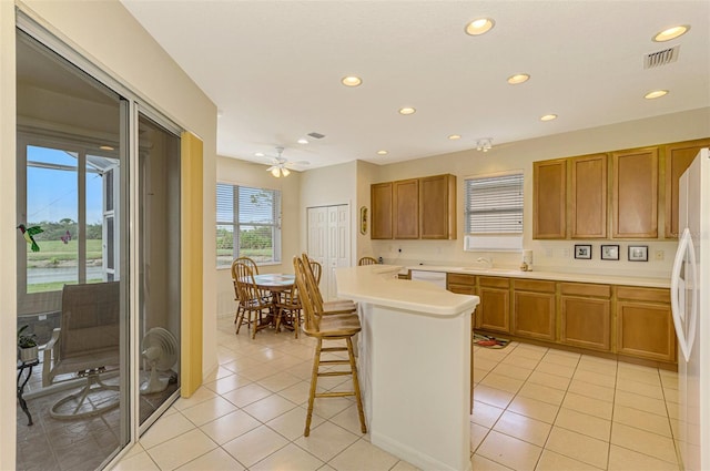 kitchen with a kitchen breakfast bar, white appliances, ceiling fan, light tile patterned floors, and a center island