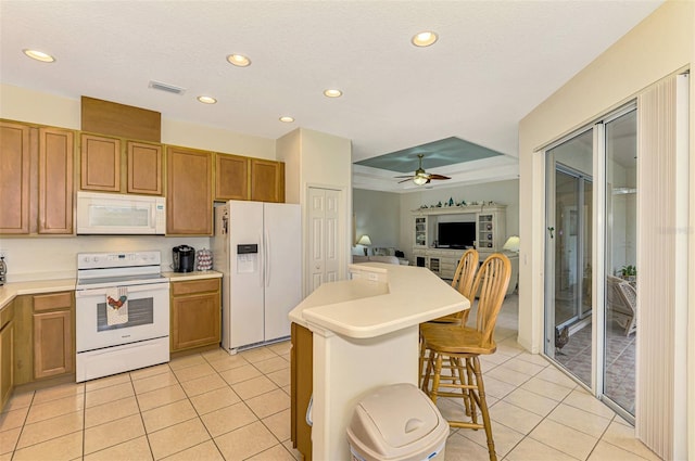 kitchen with ceiling fan, a kitchen island, white appliances, a kitchen bar, and light tile patterned floors