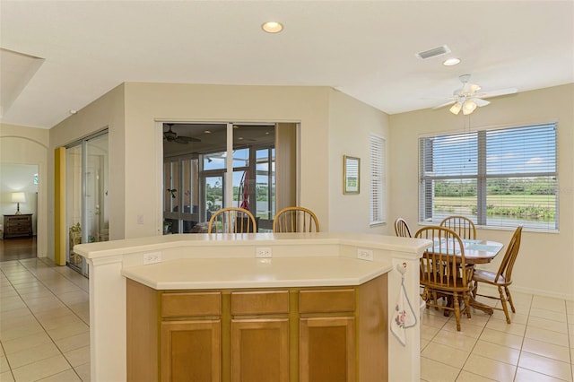 kitchen with ceiling fan, an island with sink, and light tile patterned floors