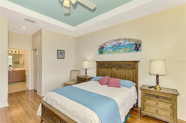 bedroom with ceiling fan, light wood-type flooring, and ensuite bath