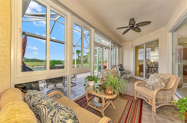 sunroom / solarium featuring ceiling fan and a water view