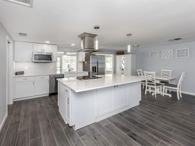 kitchen with a large island, dark wood-type flooring, pendant lighting, and appliances with stainless steel finishes