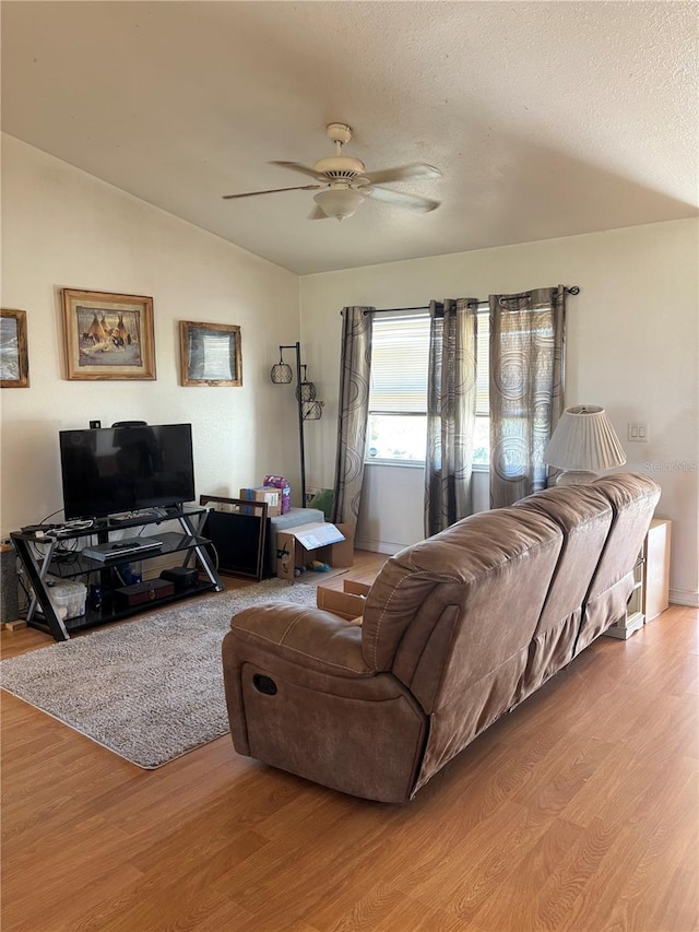 living room featuring a textured ceiling, light hardwood / wood-style floors, vaulted ceiling, and ceiling fan