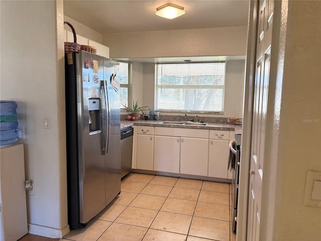 kitchen featuring sink, white cabinets, light tile patterned flooring, and appliances with stainless steel finishes