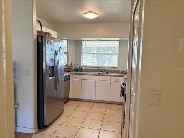 kitchen featuring a textured ceiling, stainless steel appliances, sink, white cabinets, and light tile patterned flooring