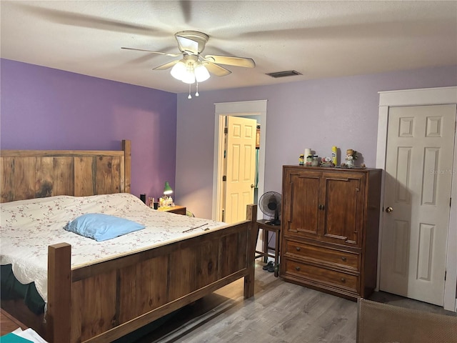 bedroom featuring ceiling fan, wood-type flooring, and a textured ceiling