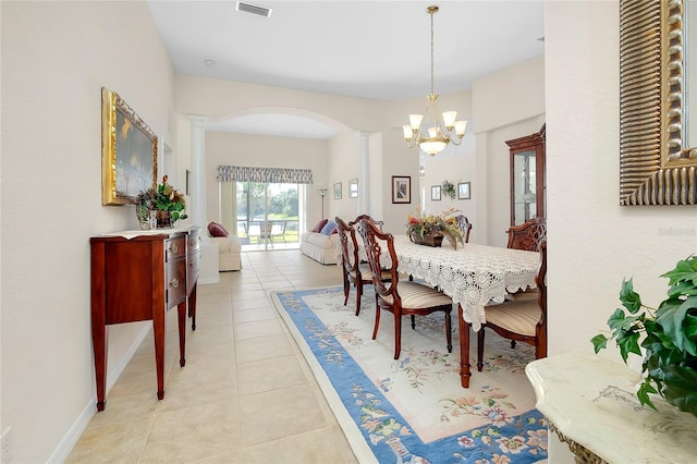 dining area with ornate columns, light tile patterned floors, and an inviting chandelier