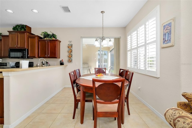 tiled dining room with an inviting chandelier and sink