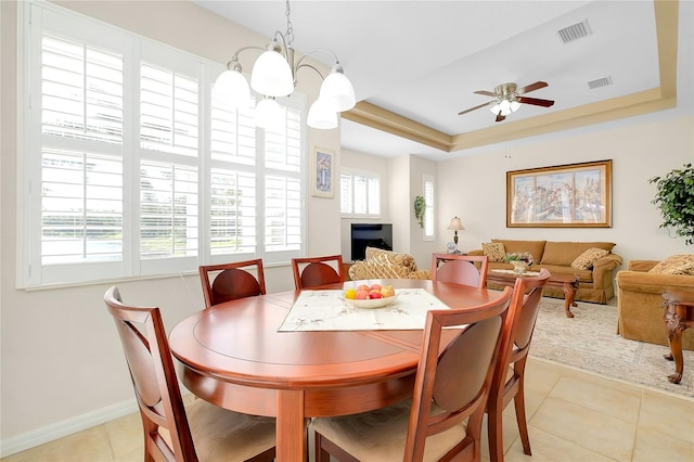 tiled dining room with a raised ceiling and ceiling fan with notable chandelier