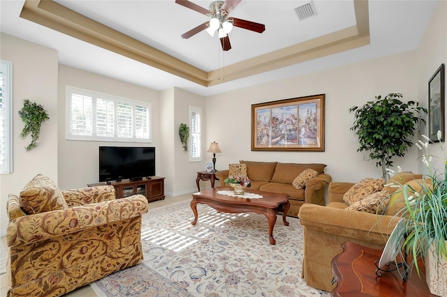 living room with a tray ceiling and ceiling fan