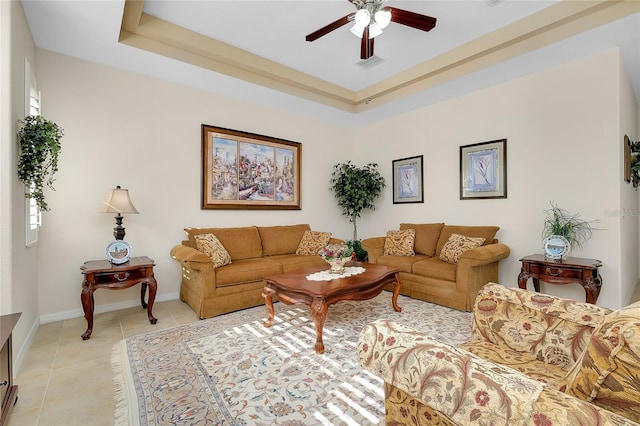 living room with ceiling fan, light tile patterned floors, and a tray ceiling