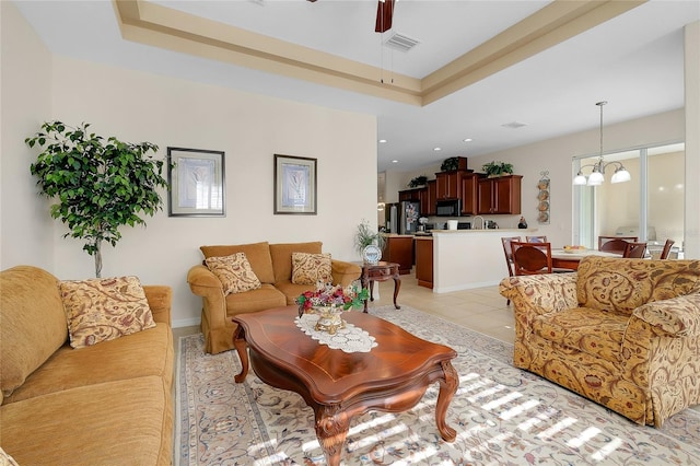 living room featuring light tile patterned flooring and ceiling fan with notable chandelier