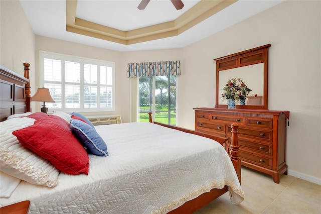 tiled bedroom featuring access to exterior, a tray ceiling, multiple windows, and ceiling fan