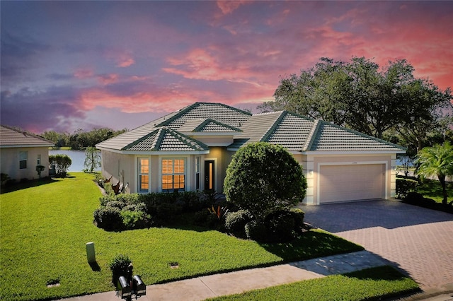 view of front facade with a water view, a garage, and a lawn