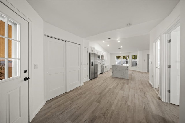 606 Marcus St Unit 26, Venice, FL 34285 - kitchen with stainless steel appliances, vaulted ceiling, white cabinetry, light wood-type flooring, and a kitchen island