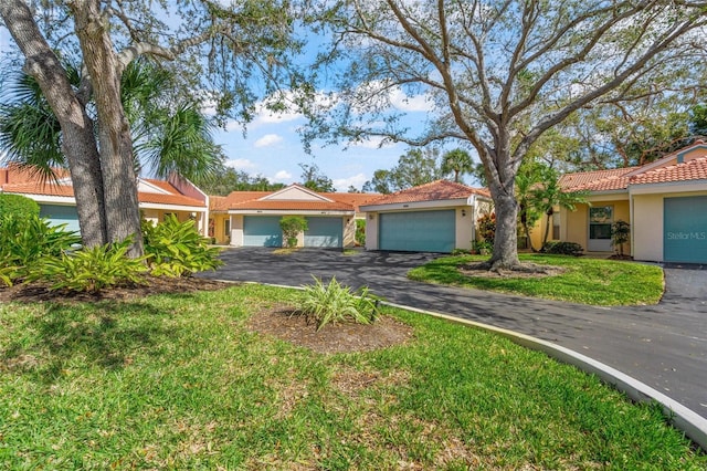 606 Marcus St Unit 26, Venice, FL 34285 - view of front of property featuring stucco siding, a tile roof, asphalt driveway, an attached garage, and a front lawn