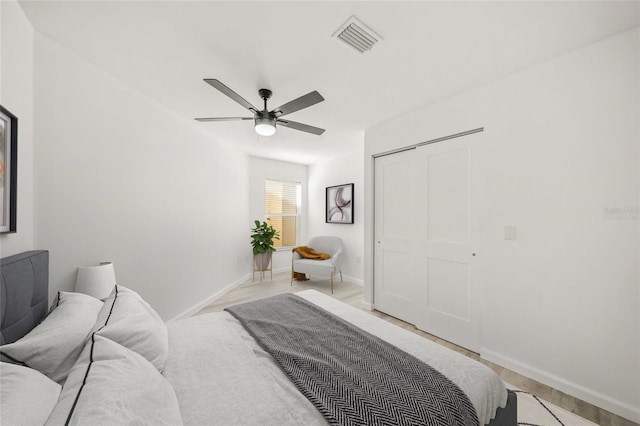 bedroom featuring a closet, a barn door, ceiling fan, and light wood-type flooring