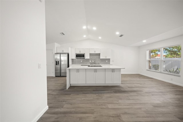 kitchen with white cabinets, appliances with stainless steel finishes, hardwood / wood-style flooring, and a center island with sink