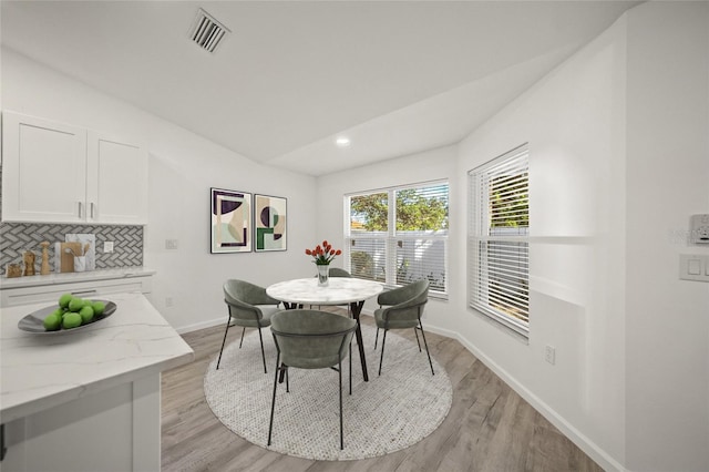 dining room with lofted ceiling and light wood-type flooring