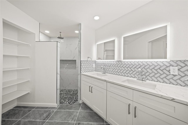 bathroom featuring a tile shower, backsplash, tile patterned flooring, and vanity