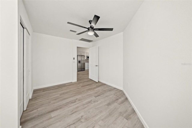 unfurnished bedroom featuring a closet, stainless steel fridge with ice dispenser, light hardwood / wood-style flooring, and ceiling fan