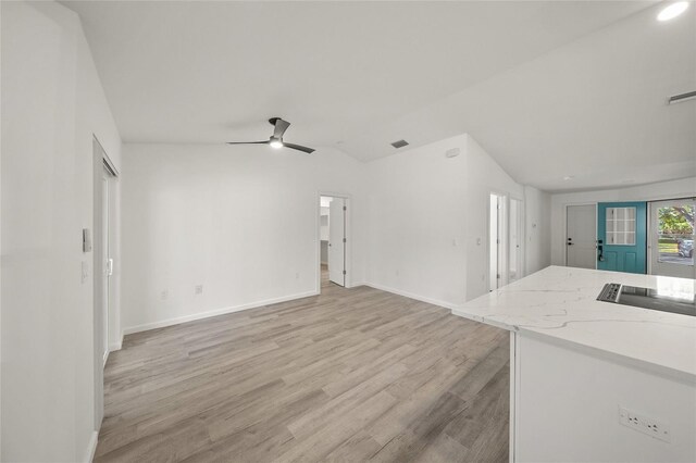 unfurnished living room with vaulted ceiling, ceiling fan, and light wood-type flooring