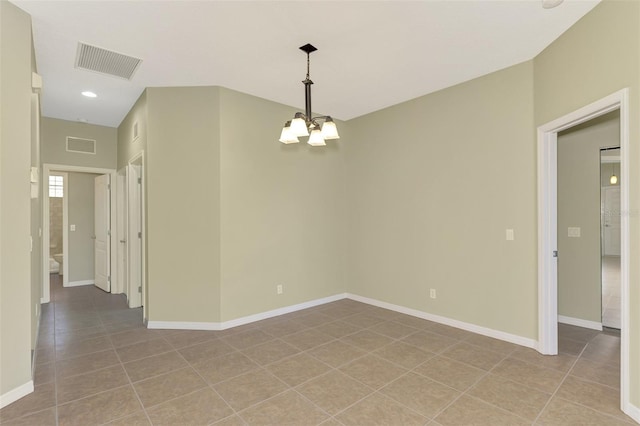 tiled spare room with a notable chandelier