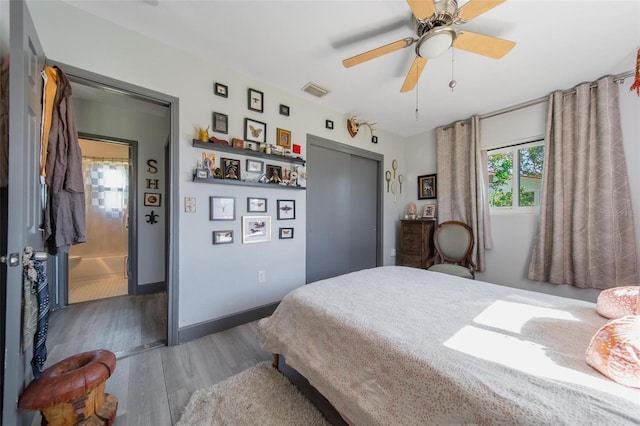 bedroom with ceiling fan, ensuite bathroom, dark hardwood / wood-style flooring, and a closet