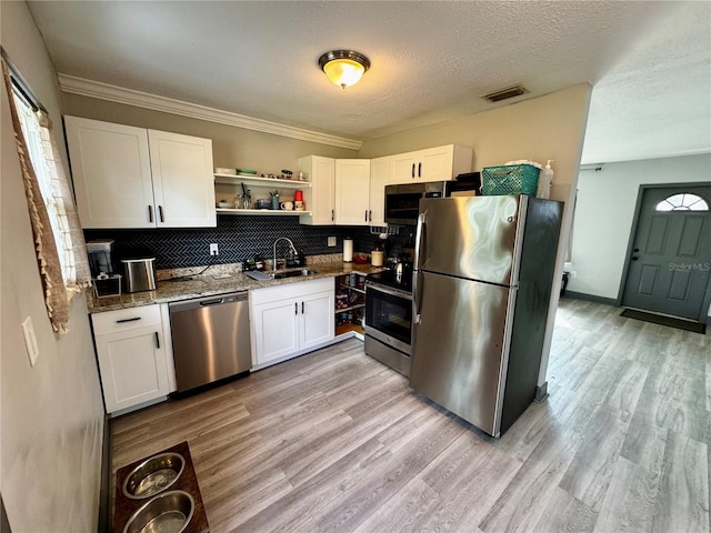 kitchen with white cabinetry, light hardwood / wood-style floors, stainless steel appliances, backsplash, and sink