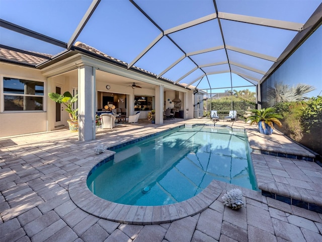 view of swimming pool featuring glass enclosure, ceiling fan, and a patio area