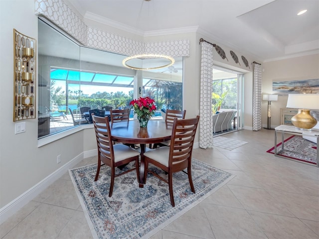 tiled dining space featuring a raised ceiling, a wealth of natural light, and crown molding