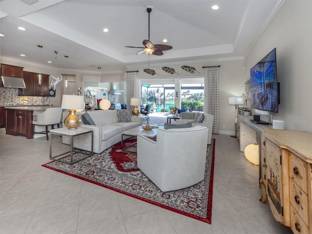 tiled living room with ceiling fan, crown molding, sink, and a tray ceiling