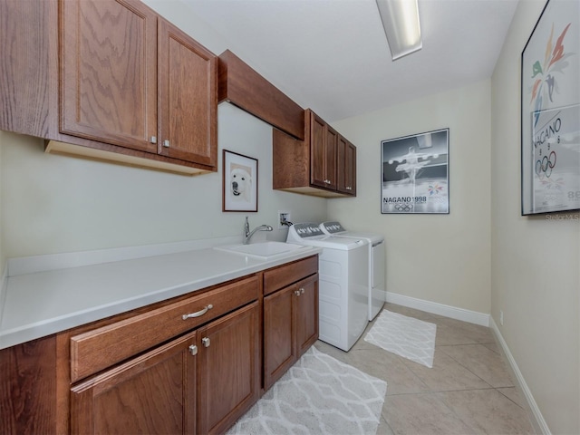 laundry room with washer and clothes dryer, sink, light tile patterned floors, and cabinets