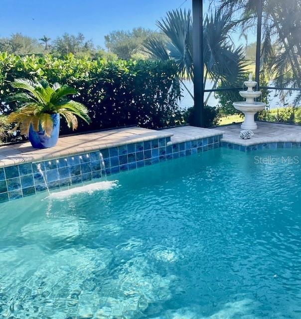 view of swimming pool featuring glass enclosure and pool water feature