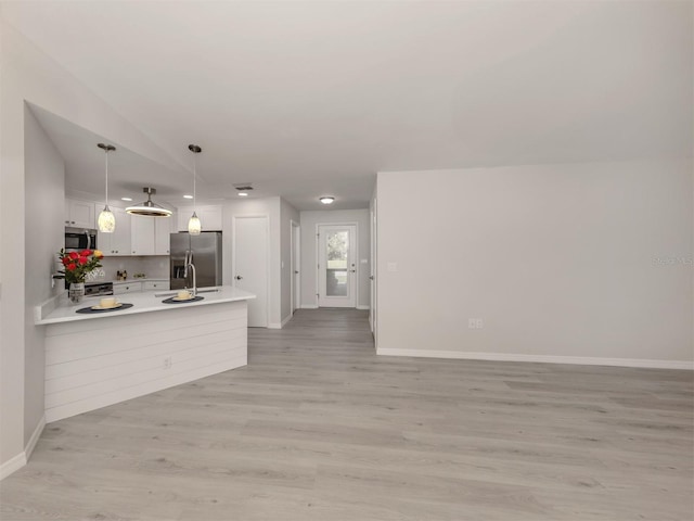 kitchen featuring white cabinets, decorative light fixtures, stainless steel appliances, and light hardwood / wood-style floors