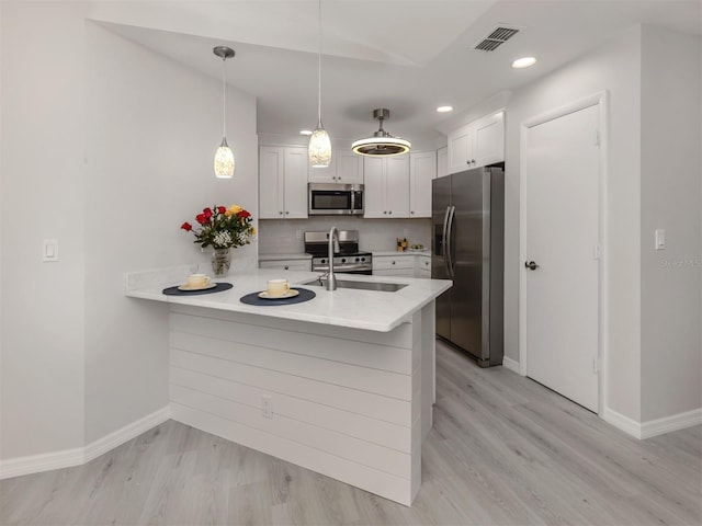 kitchen featuring kitchen peninsula, stainless steel appliances, white cabinetry, and sink