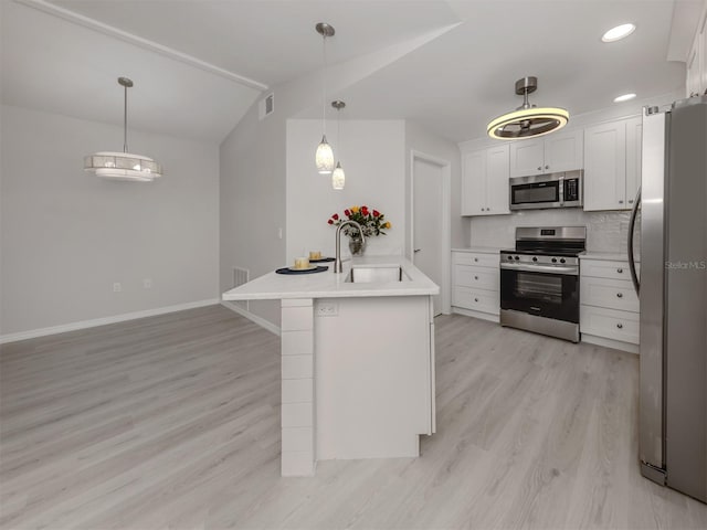 kitchen with white cabinets, vaulted ceiling, light hardwood / wood-style floors, kitchen peninsula, and stainless steel appliances