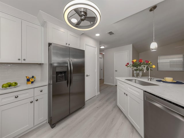 kitchen with sink, light hardwood / wood-style flooring, appliances with stainless steel finishes, tasteful backsplash, and white cabinetry