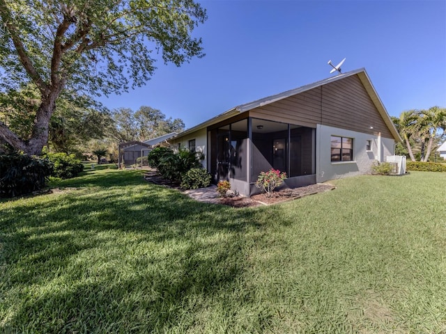 rear view of property featuring a yard and a sunroom