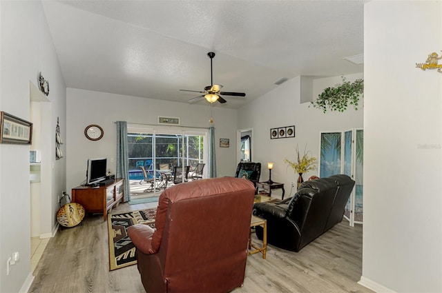 living room featuring ceiling fan, light wood-type flooring, a textured ceiling, and vaulted ceiling